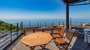 Een houten terras met een tafel en stoelen met uitzicht op de kust.