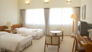 A hotel room with two beds, a desk, a chair, a television, and a lamp. - Ono Himawari Hotel (Ono)