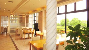 A spacious hotel lobby with a large spiral column, multiple seating areas, and large windows offering a view of the outdoors. - Ono Himawari Hotel (Ono)