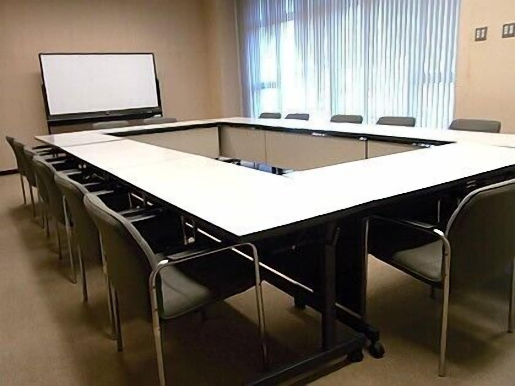 A conference room with a long table, chairs, a projector, and a whiteboard.