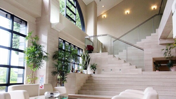 A spacious living area with a high ceiling, a staircase, and large windows allowing natural light. - Ono Himawari Hotel (Ono)