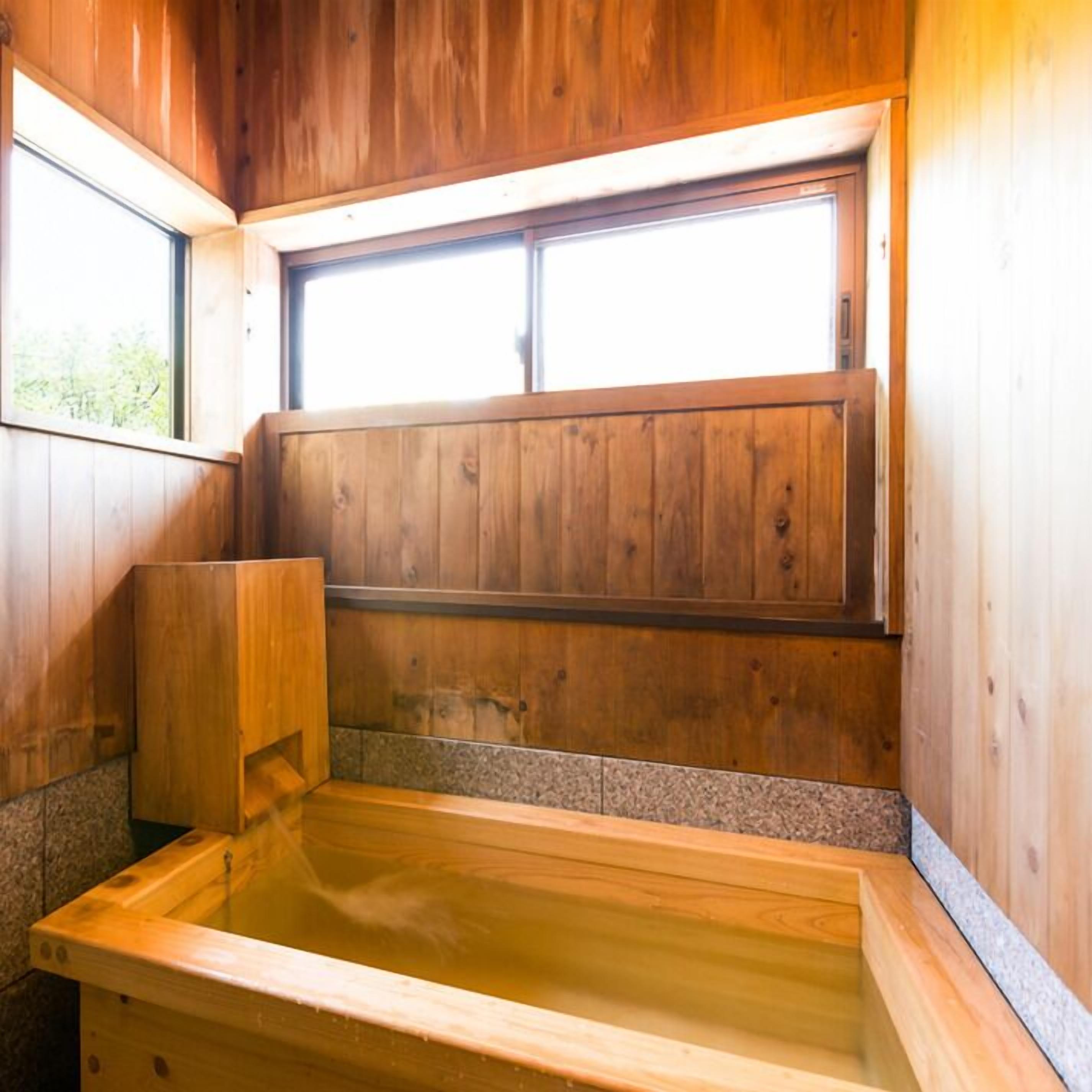 A wooden sauna with a large window, a wooden bench, and a stone-tiled floor.