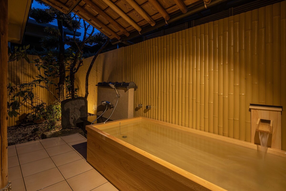 A hot tub in a covered outdoor area with bamboo walls and a tiled floor.