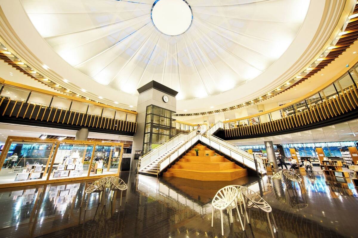 A spacious atrium with a central staircase, glass railings, and a modern ceiling design.