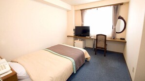 Ein Hotelzimmer mit einem Bett, einem Schreibtisch mit Fernseher, einem Sessel, einer kleinen Kühlbox und einem Telefon.