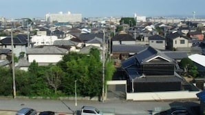 Ein Wohngebiet mit traditionellen japanischen Häusern, wolkenlosem Himmel und weiter Aussicht auf eine Stadtlandschaft.