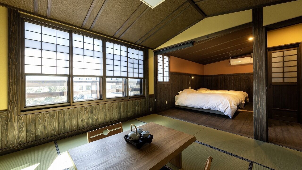 A traditional Japanese-style room with tatami flooring, a low wooden bed, and a sliding door.