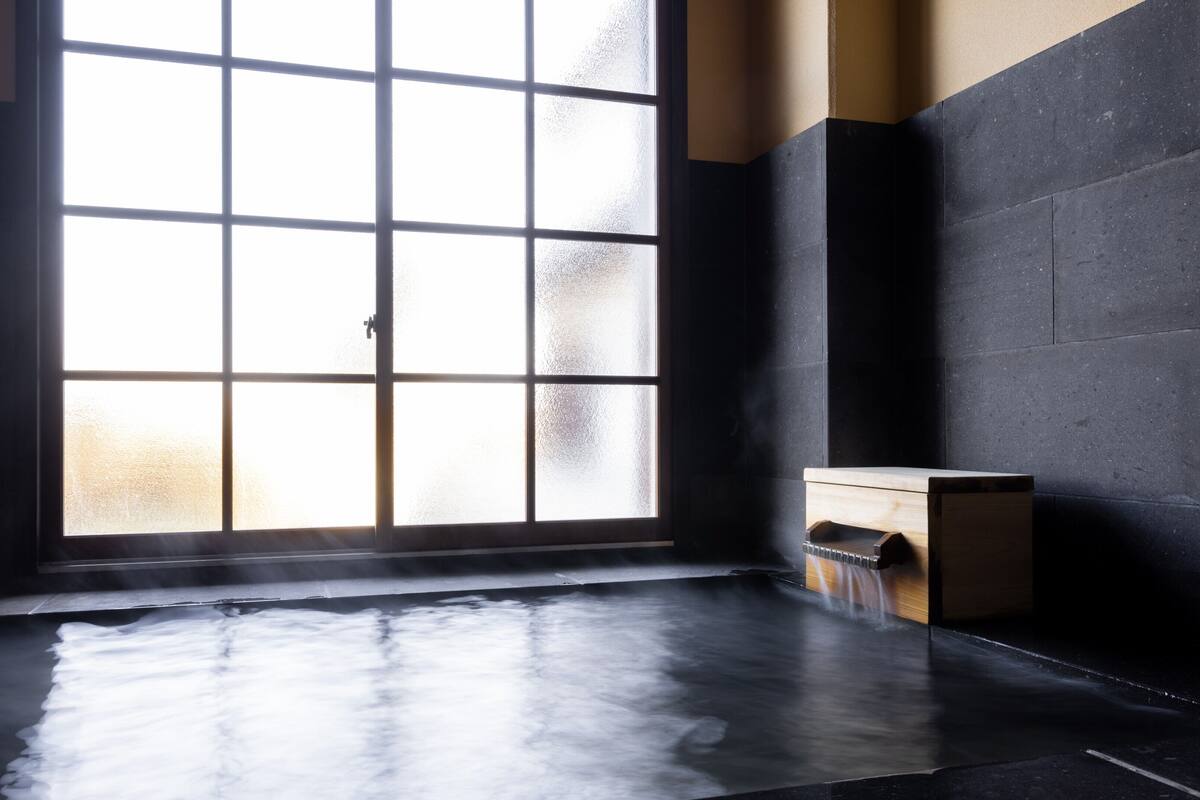 Una habitación con un amplio ventanal esmerilado, un banco de madera y un suelo de baldosas.