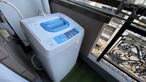 A compact, white washing machine with a digital control panel, located on a balcony with a metal railing and a view of a cityscape. - 3 Units Same Floor, 30sec Tsutenkaku/1 stop Namba2 (Naniwa-ku, Osaka City)