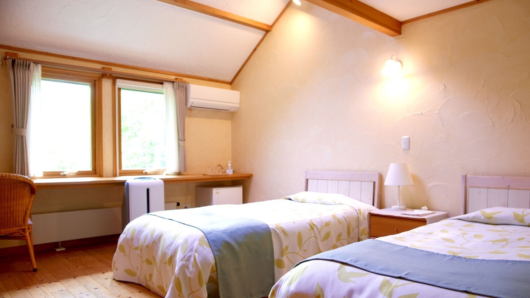 Un dormitorio con dos camas, un escritorio, una silla y una ventana con cortinas.