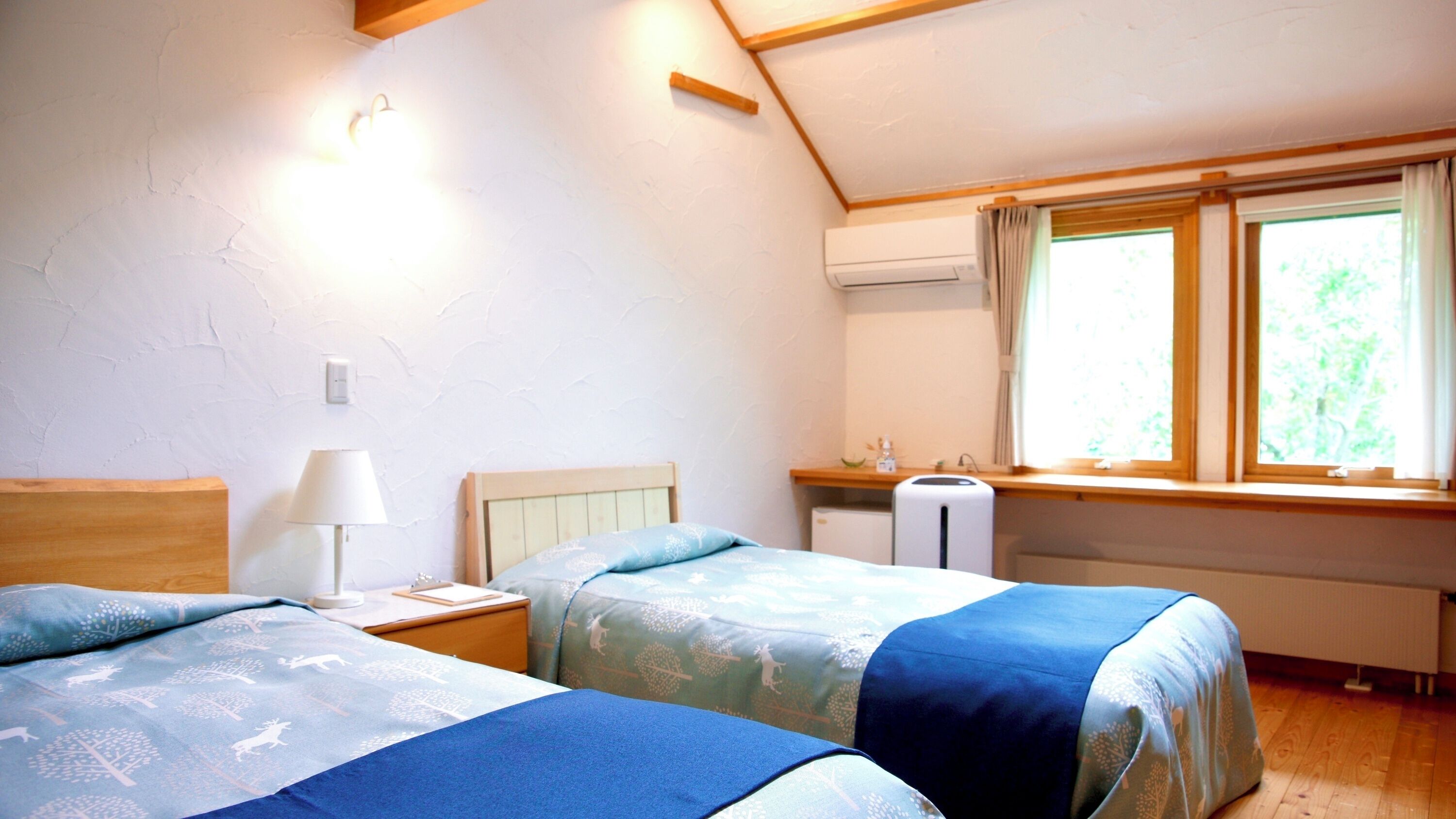 Un dormitorio con dos camas, un escritorio, una lámpara y una ventana con cortinas.