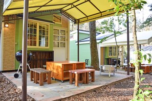 An outdoor patio area with a covered seating area, a grill, and a wooden table. - Pica Resort Fuji Yoshida (Fujiyoshida)