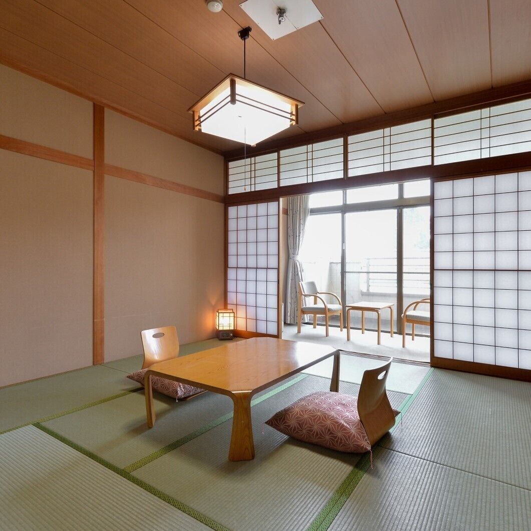 Une pièce de style japonais traditionnel, avec un sol recouvert de tatamis, une petite table en bois et des portes coulissantes en papier de riz (shoji).