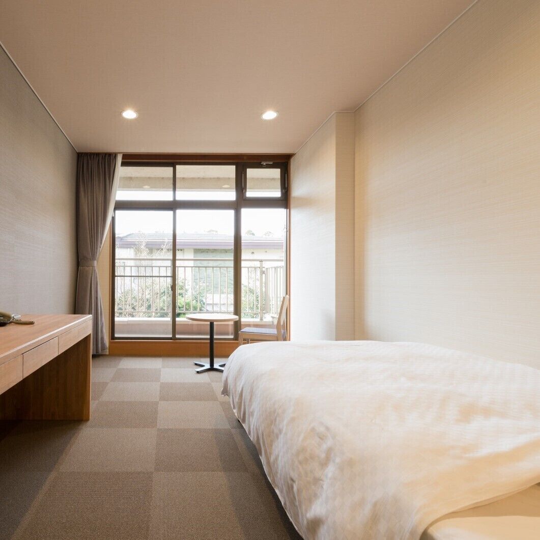 Une chambre d’hôtel avec un lit, un bureau, une chaise et un balcon offrant une vue.