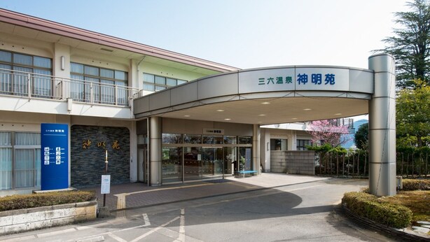 A building with a curved entrance, signage in a foreign language, and a blue information board. - Saburoku Onsen Shinmeien (Sabae)
