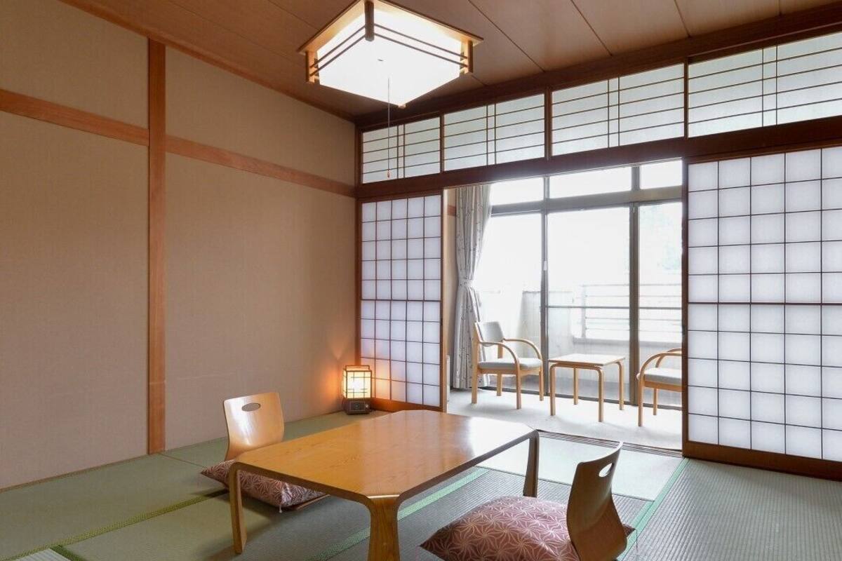 A traditional Japanese room with tatami flooring, a low table, and sliding doors.