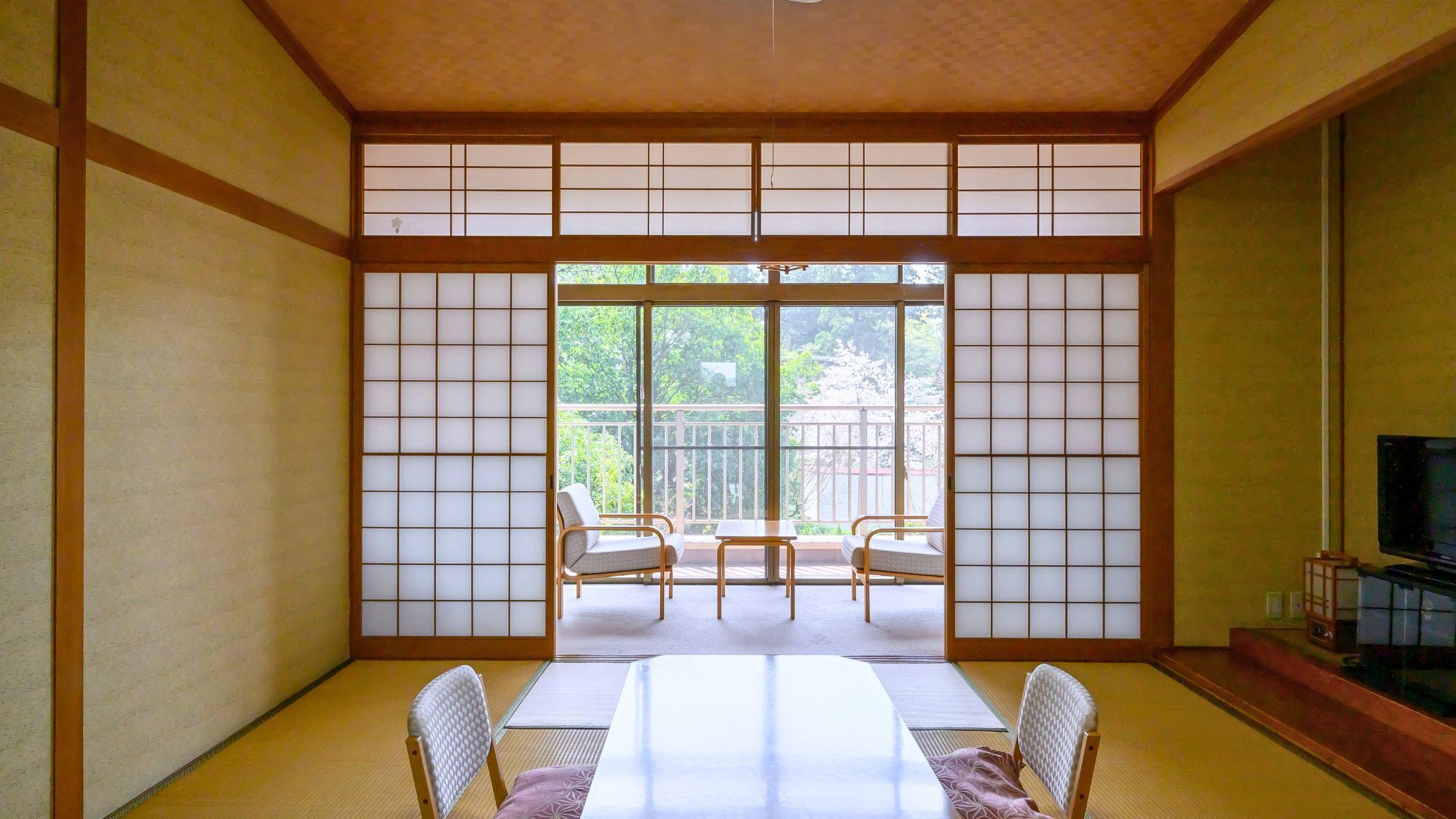 Une pièce de style japonais traditionnel, avec un sol recouvert de tatamis, une table basse et des portes coulissantes.
