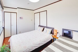 Habitación de hotel con cama, mesita de noche, televisor y un cartel de 'No Fumar'.