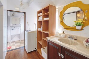 Un baño con tocador de madera, un espejo grande y un microondas empotrado.