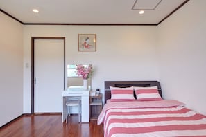 A bedroom with a bed, a desk, and a chair.