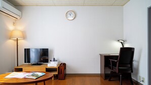 Een moderne woonkamer met een flatscreen televisie, een houten salontafel, een lamp, een bureau en een stoel.