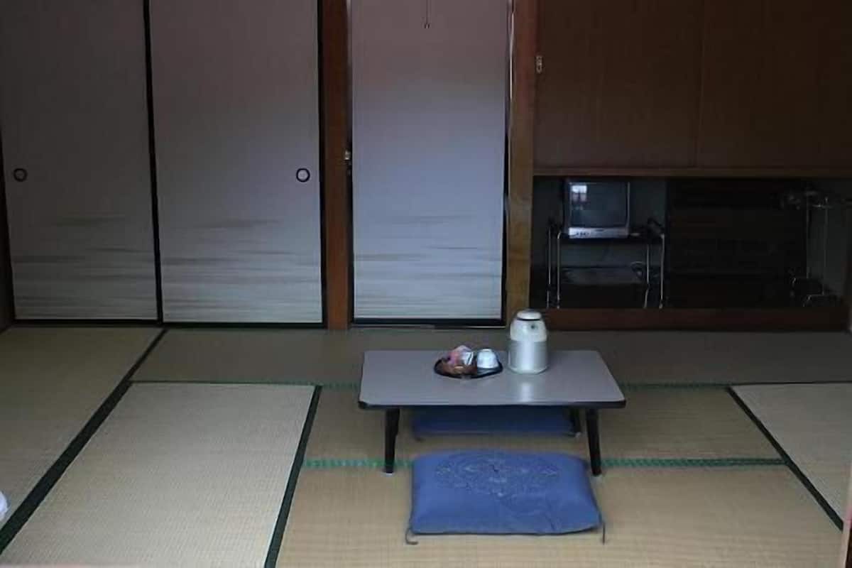 A tatami mat room with a table, a pillow, and a small table with a cup and saucer.