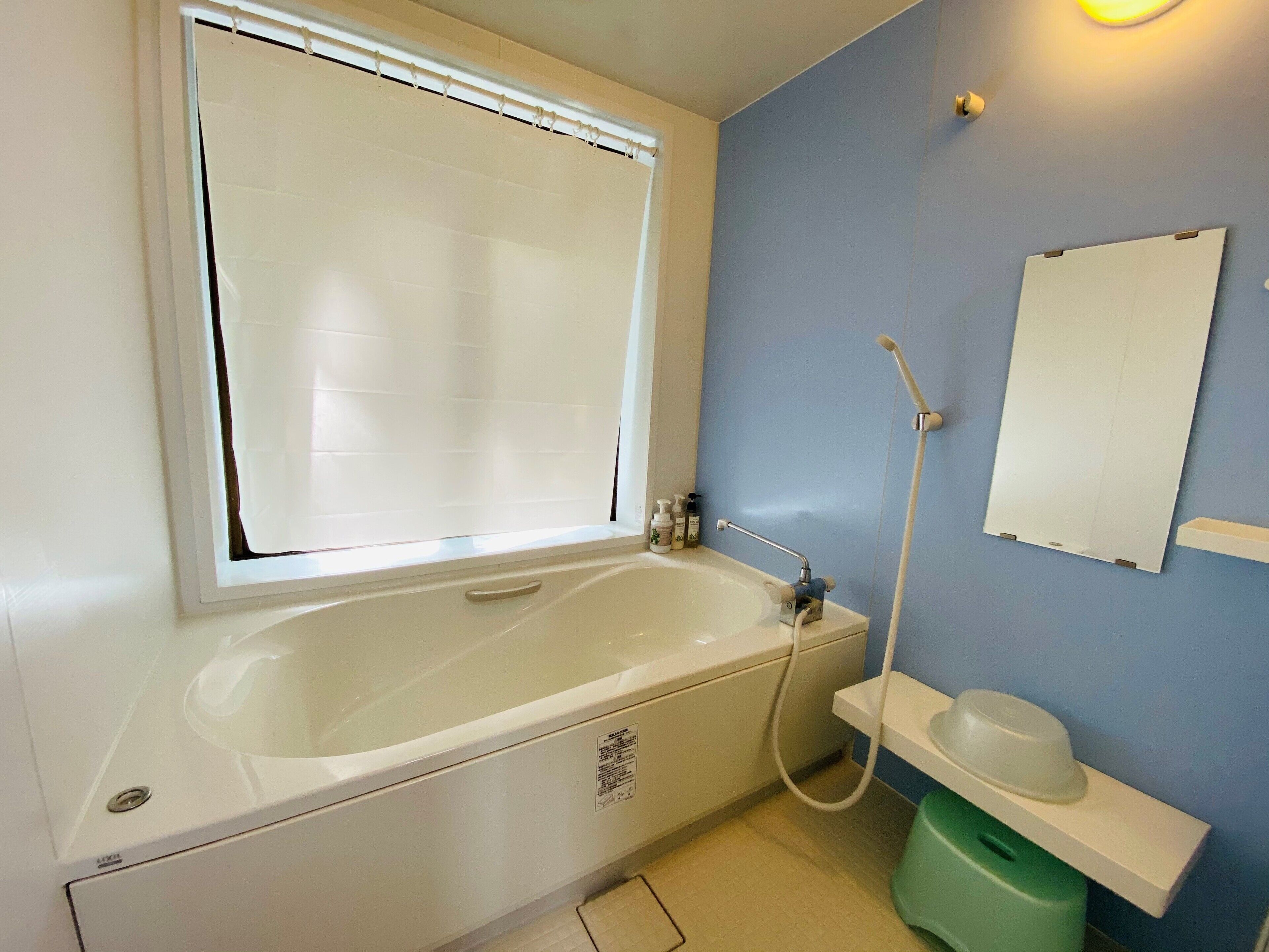 A bathroom with a bathtub, a window, a sink, and a mirror.
