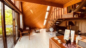 Una camera mansardata accogliente con soffitto in legno, una scala, una ventola e un cartello di benvenuto.