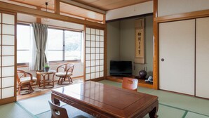 A traditional Japanese room with tatami flooring, a low wooden table, and sliding doors. - Ryokan Umenoya (Bungotakada)