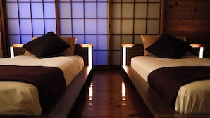 A room with two beds, wooden flooring, and a traditional Japanese shoji screen in the background. - Atami Kaiun (Atami)