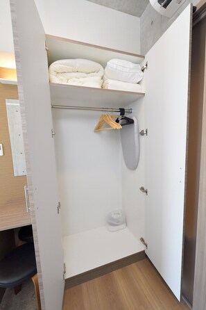 Een kleine badkamer met een douche, toilet en een plank met opgevouwen handdoeken.