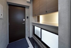 A hallway with a dark door, a light switch, a thermostat, and a small window with a white frame.