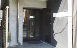 A modern entrance with a glass door, a metal gate, and a concrete pillar.