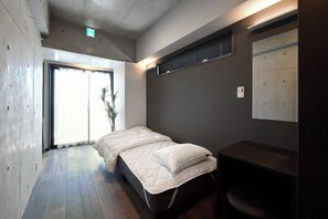 Een moderne slaapkamer met een bed, een bureau en een raam met zonwering.