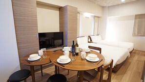 A hotel room with a dining area, a TV, a bed, and a minibar. - Prime Suites Tokyo (Tokyo)