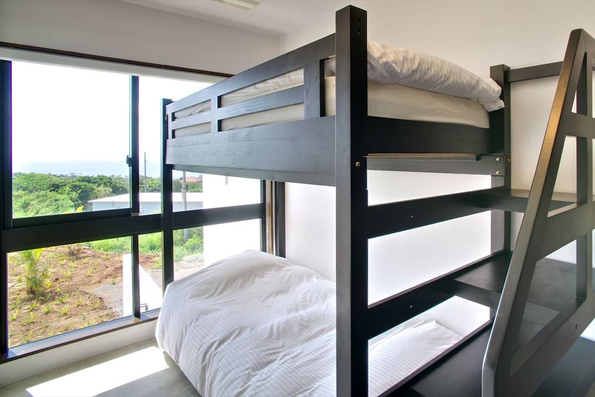 A bunk bed with a view of a garden through a large window.