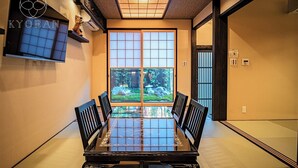 A traditional Japanese-style room with tatami mat flooring, a low table with a glass top, and sliding doors leading to a garden. - Kyoran-gengetsu (Kyoto)