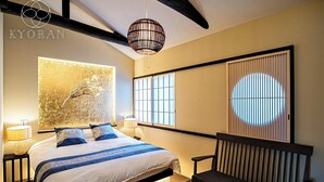 A modern bedroom with a bed, bedside lamps, a wall-mounted artwork, a window with blinds, and a bench. - Kyoran-gengetsu (Kyoto)