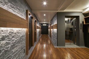 A hallway with wooden flooring, stone walls, and doors leading to rooms. - Shinjuku City Hotel N. U. T. S Tokyo (Tokyo)