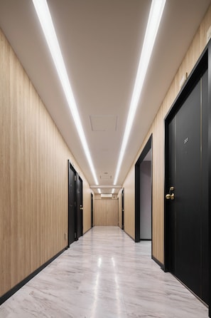 A hallway with wooden panel walls, black doors, and a marble floor. - Shinjuku City Hotel N. U. T. S Tokyo (Tokyo)