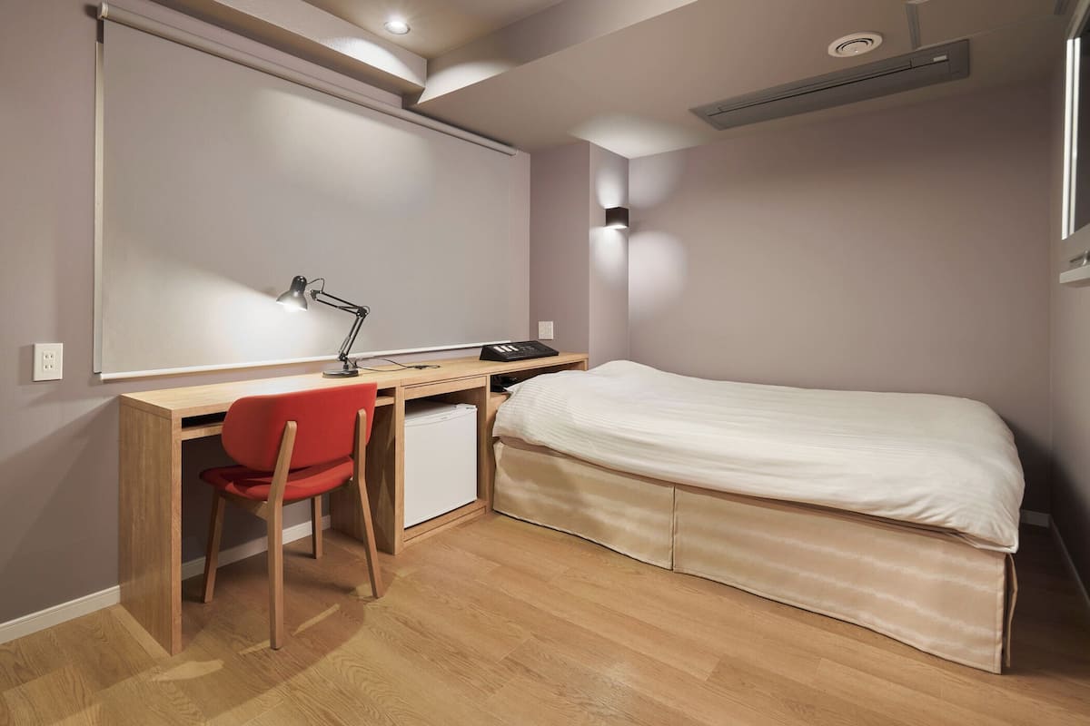 A bedroom with a bed, a desk, and a chair.