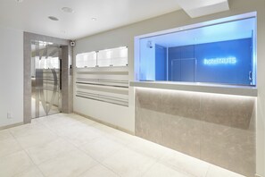 A modern hotel reception area with a glass door, a reception desk, and a neon sign reading "hotel NUTS". - Shinjuku City Hotel N. U. T. S Tokyo (Tokyo)
