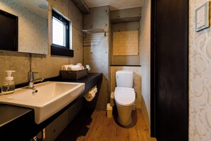 Une salle de bain avec un lavabo, des toilettes et une fenêtre.