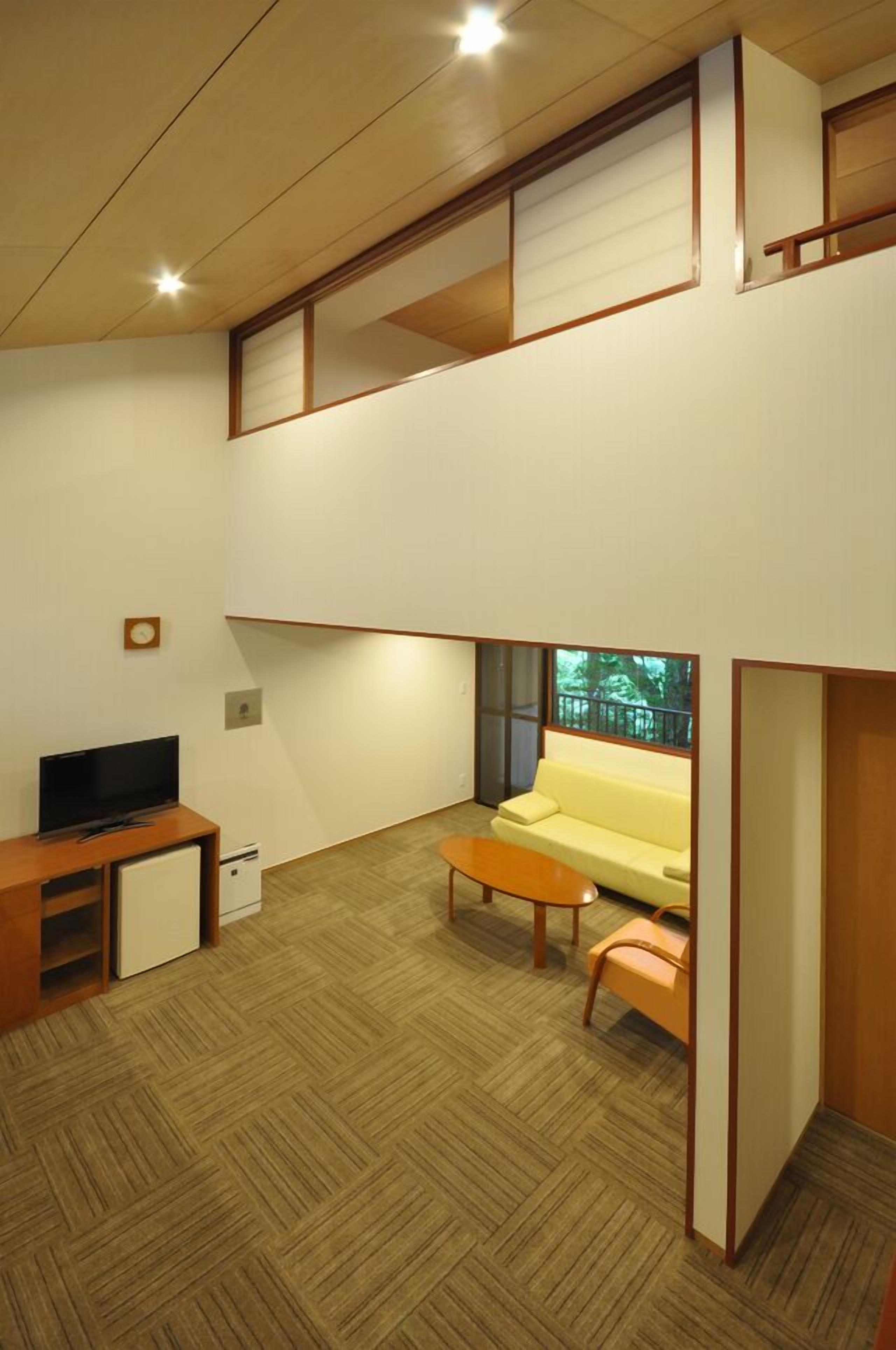 A modern living room with a sofa, a coffee table, a TV, and a small cabinet.
