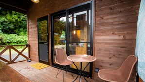 A wooden deck with two wicker chairs and a small round table, a glass door leading inside, and a wooden railing. - Shioya Onsen Shioya SPA (Minakami)