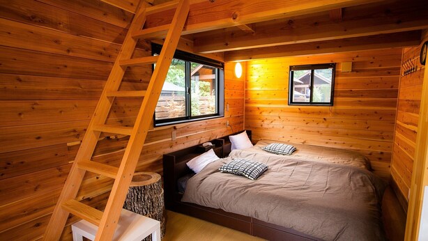 A wooden cabin bedroom with a bed, a ladder, and a small table. - Shioya Onsen Shioya SPA (Minakami)