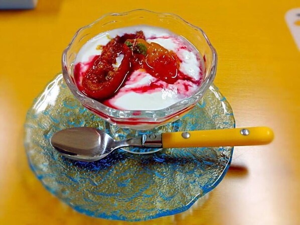A dessert in a glass bowl on a blue patterned plate with a spoon beside it.