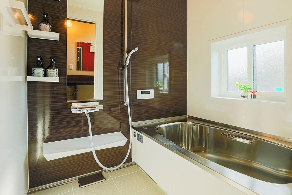 Une salle de bain moderne dotée d’une douche intégrée, d’un évier en acier inoxydable et d’une fenêtre offrant une vue agréable.