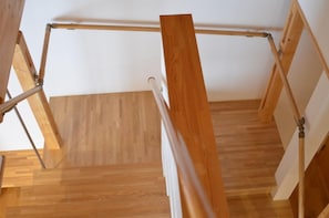 A wooden staircase with a metal handrail, leading to an upper floor. - Bliss Cottage Sakura (Kutchan)