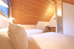 A bedroom with two beds, wooden ceiling, and a desk with a chair. - Bliss Cottage Sakura (Kutchan)